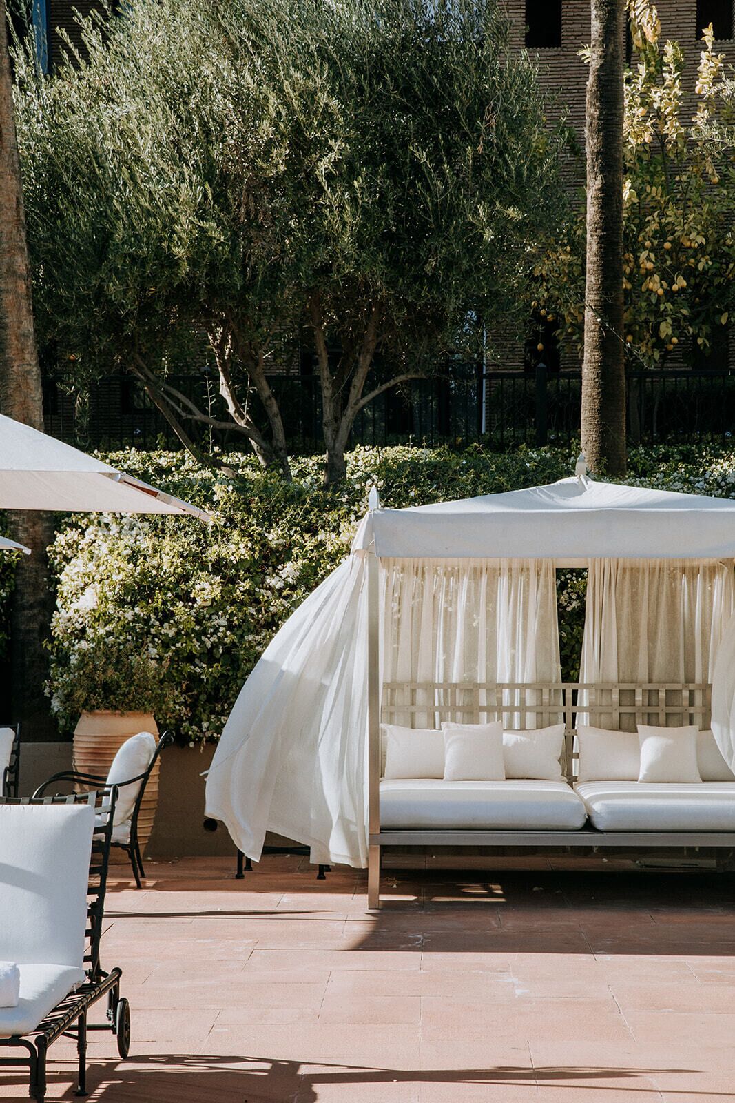 A covered outdoor seating area with a canopy, a cushioned bench, and a chair.