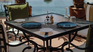 Een eettafel met stoelen, een zwembad en een palmboom op de achtergrond.
