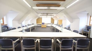 Un salón de conferencias con una larga mesa, sillas y un atril.