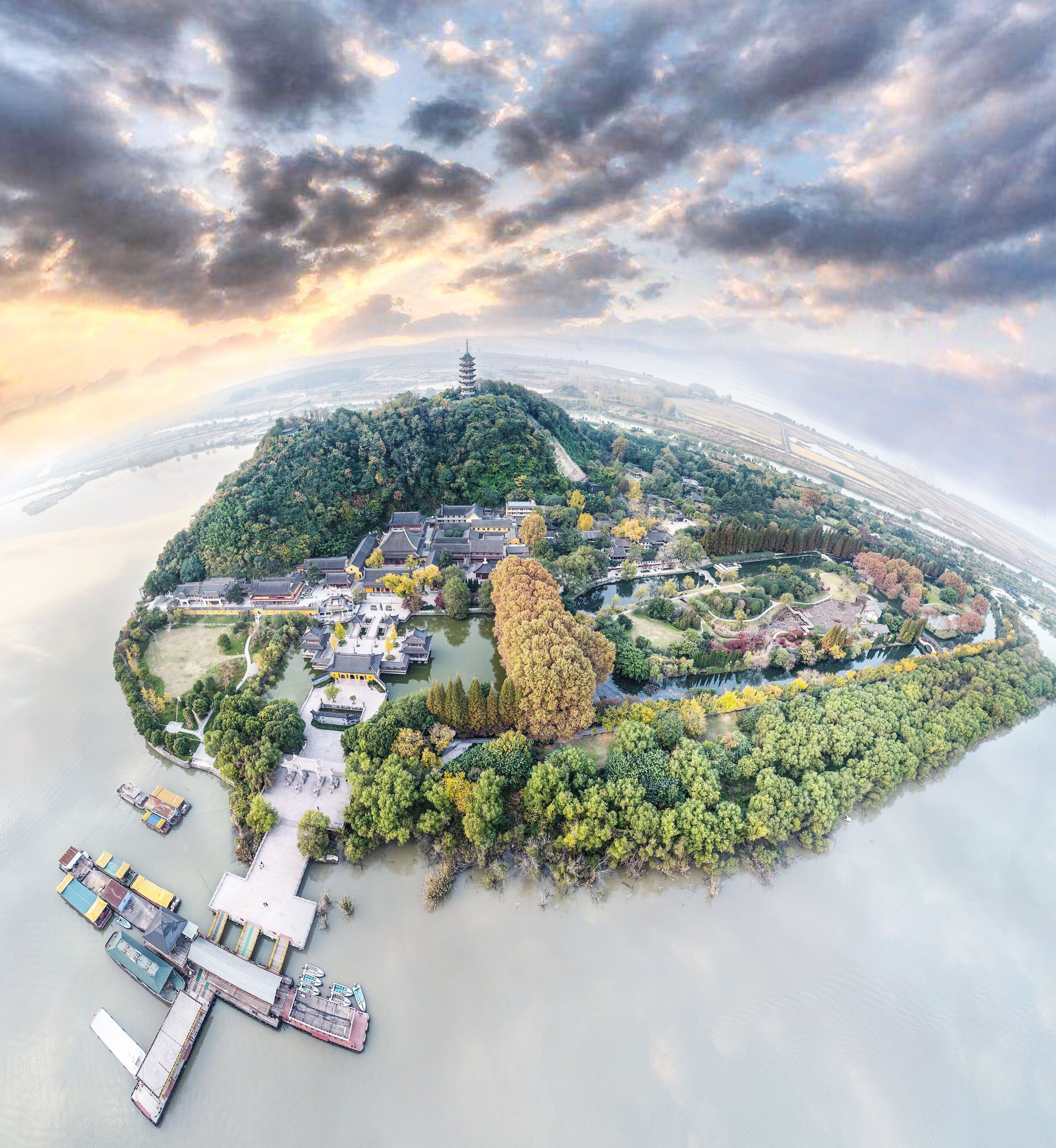 An aerial view of a traditional Chinese pagoda surrounded by lush greenery and a calm river.