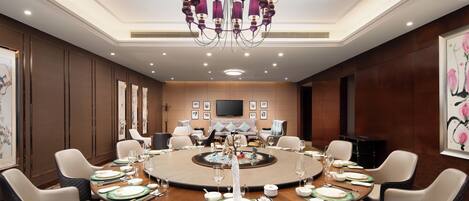 A conference room with a round table, chairs, and a chandelier.