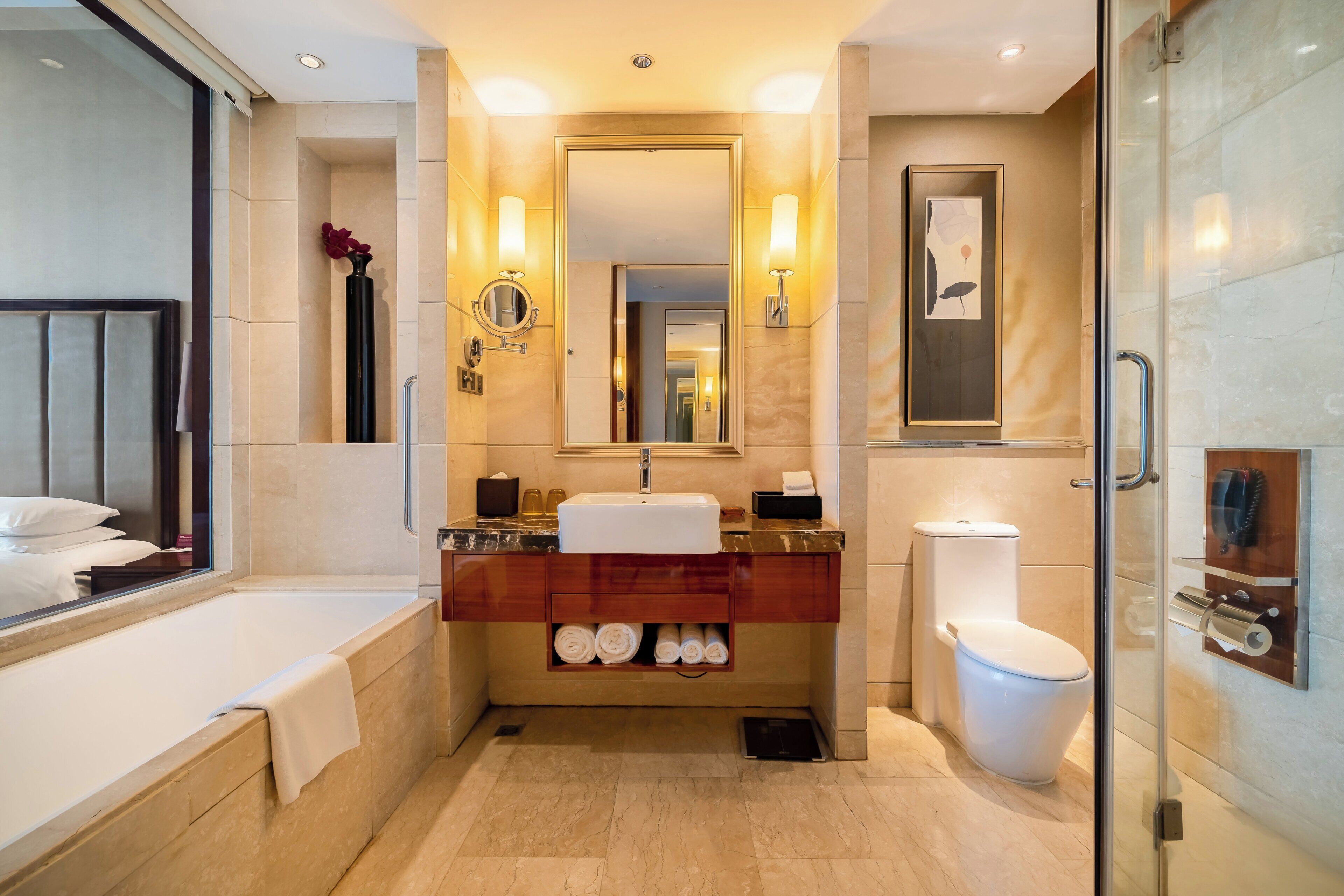 A modern bathroom with a bathtub, a sink, a toilet, and a glass-enclosed shower.