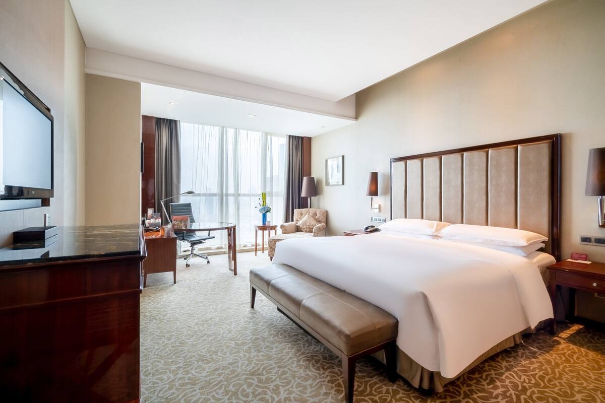 Habitación de hotel con una cama grande, un escritorio con computadora, una silla y televisión.