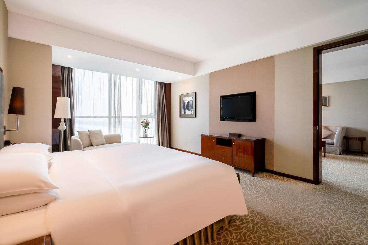 Habitación de hotel con una cama grande, televisión de pantalla plana, escritorio y vistas al exterior.
