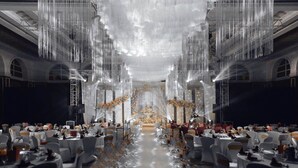 Un salón de banquetes con mesas dispuestas para un evento formal, con un escenario central y elegantes arreglos florales.