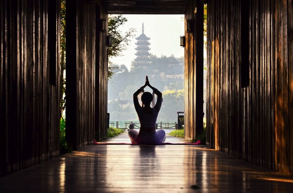 A person in a meditative pose in a corridor with traditional architecture and a pagoda in the background. - Crowne Plaza Zhenjiang by IHG (Zhenjiang)