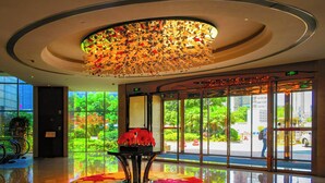A lobby with a large glass window, a decorative ceiling, and a reflective floor. - Crowne Plaza Zhenjiang by IHG (Zhenjiang)