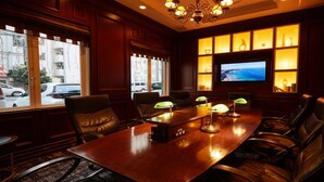 A conference room with a wooden table, leather chairs, and a television on the wall. - GRG Hotel Naha Higashimachi (Naha)