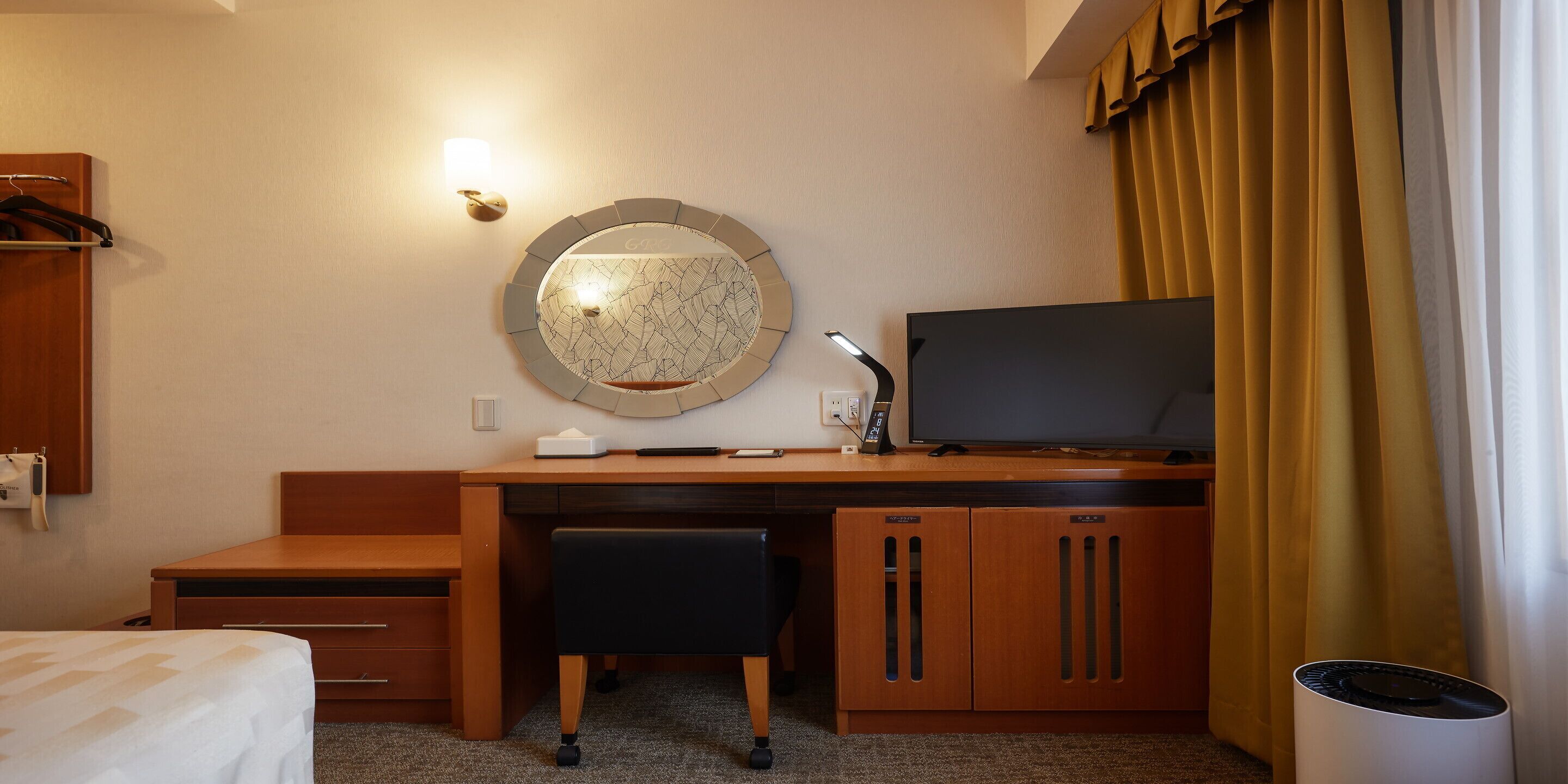 Une chambre d’hôtel avec un bureau en bois, une télévision, un miroir et un lit.
