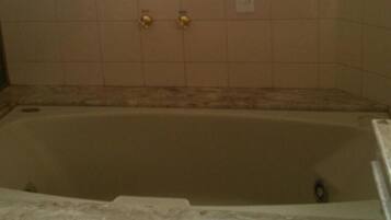 A bathtub with a tiled wall and a marble-like border.