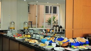 Un buffet proposant une variété d’aliments et de boissons, notamment des fruits, des sandwichs et des boissons chaudes.