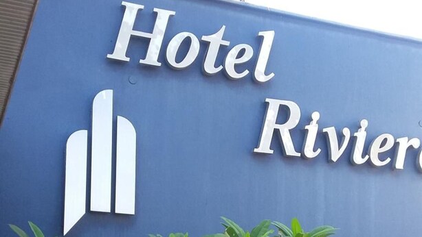 Un mur bleu sur lequel on peut lire le texte « Hôtel Riviera » et qui est orné d’une icône stylisée représentant un bâtiment.