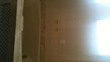 A bathroom with a tiled wall, a window, and a door.