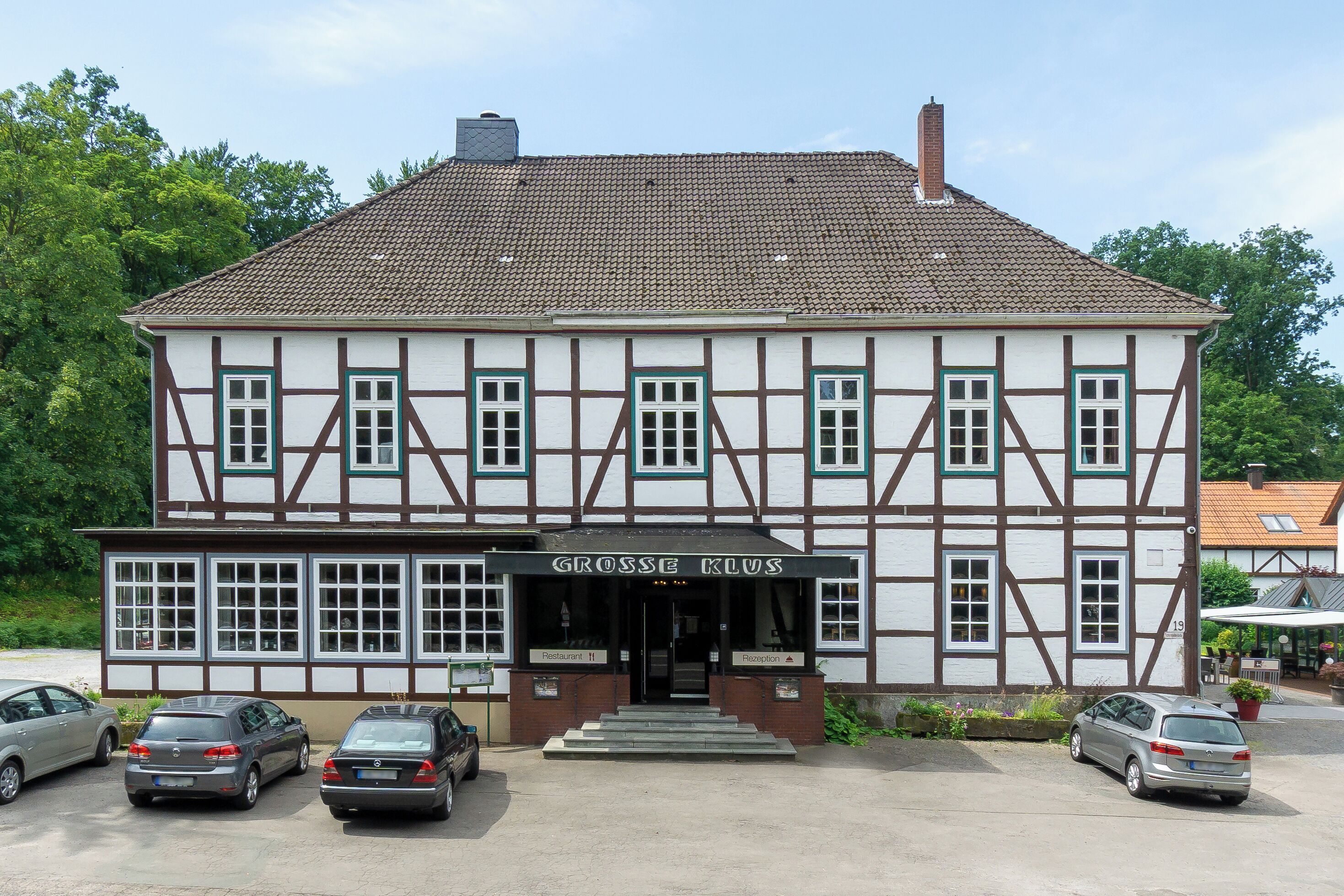 A two-story building with a sign reading "Grosse Klaus." There are three cars parked in front.