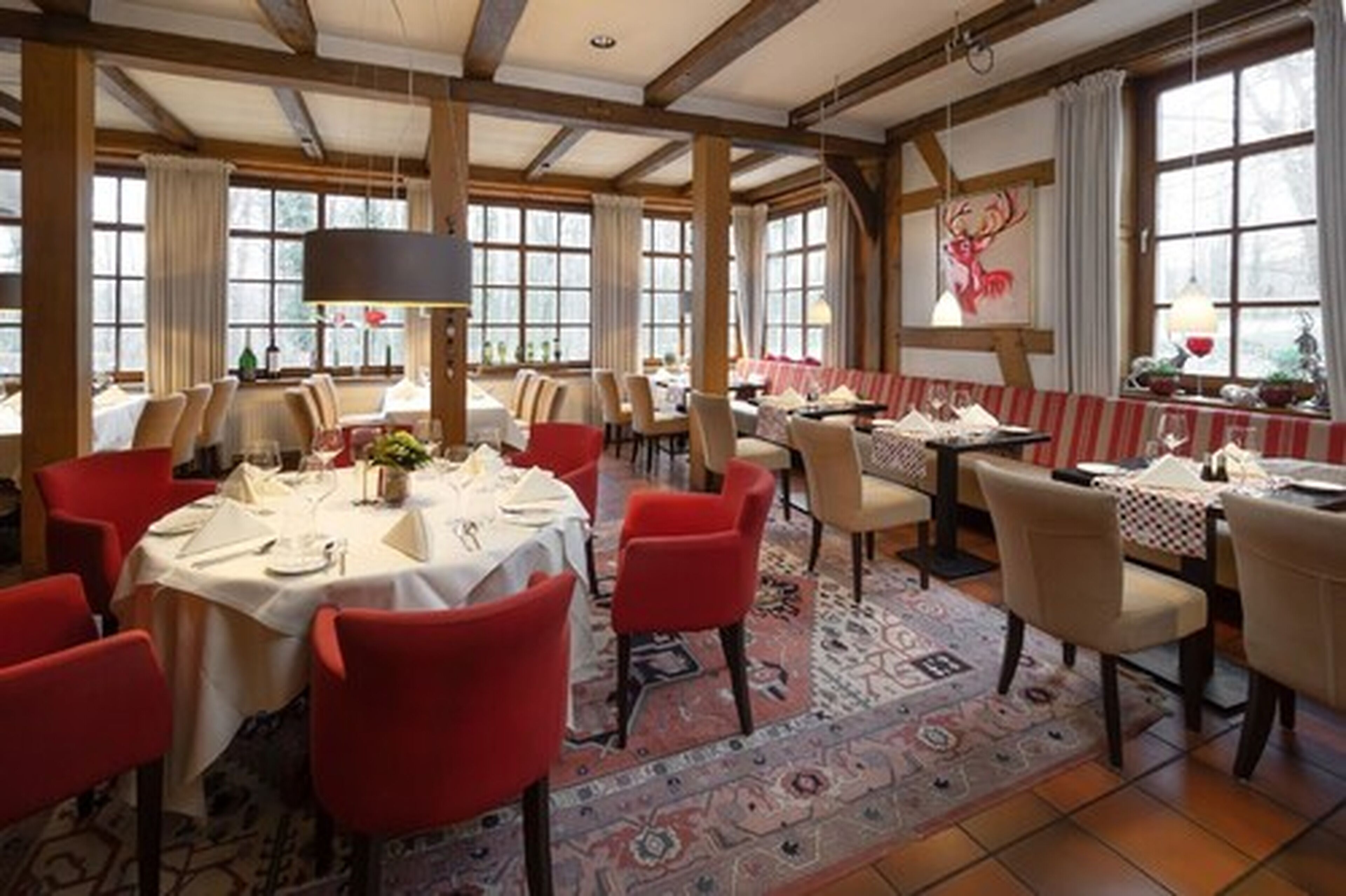 A dining area with round tables, red chairs, and a patterned carpet.