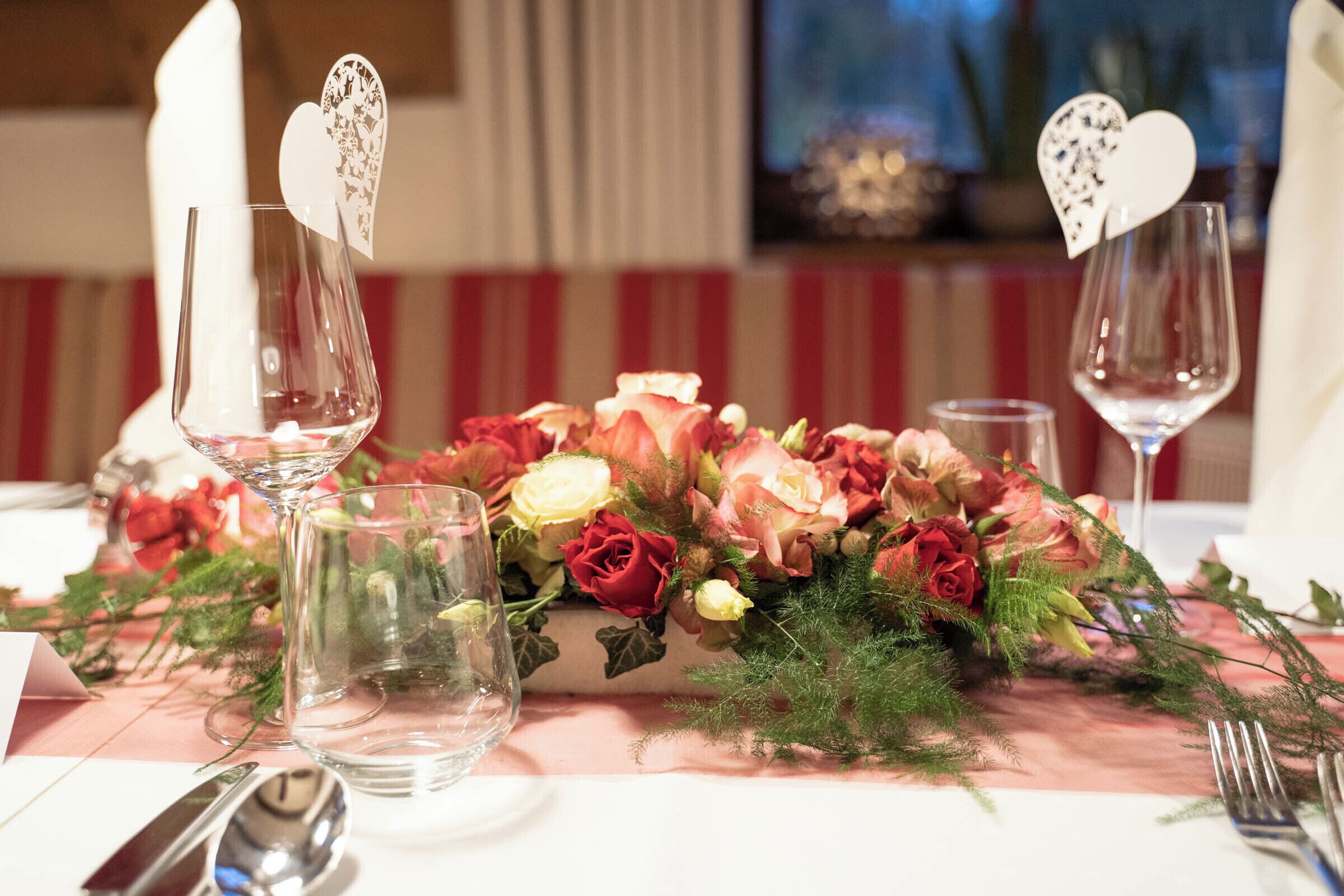 A table set with wine glasses, a floral centerpiece, and cutlery.