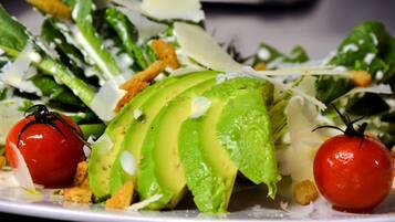 A salad with avocado slices, cherry tomatoes, and croutons on a plate.