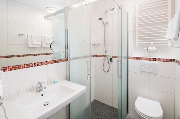 A modern bathroom with a glass-enclosed shower, a white sink, and a toilet.