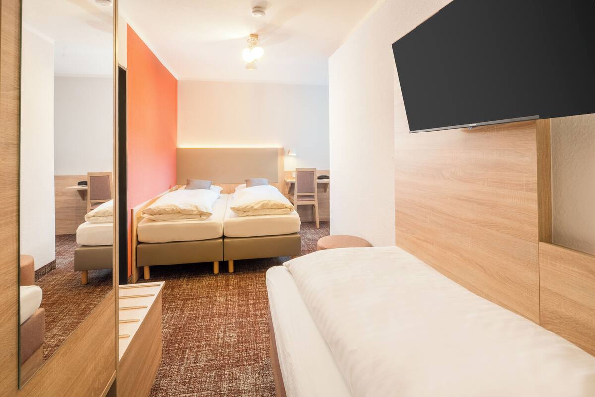 A hotel room with a bed, a desk, and a TV.