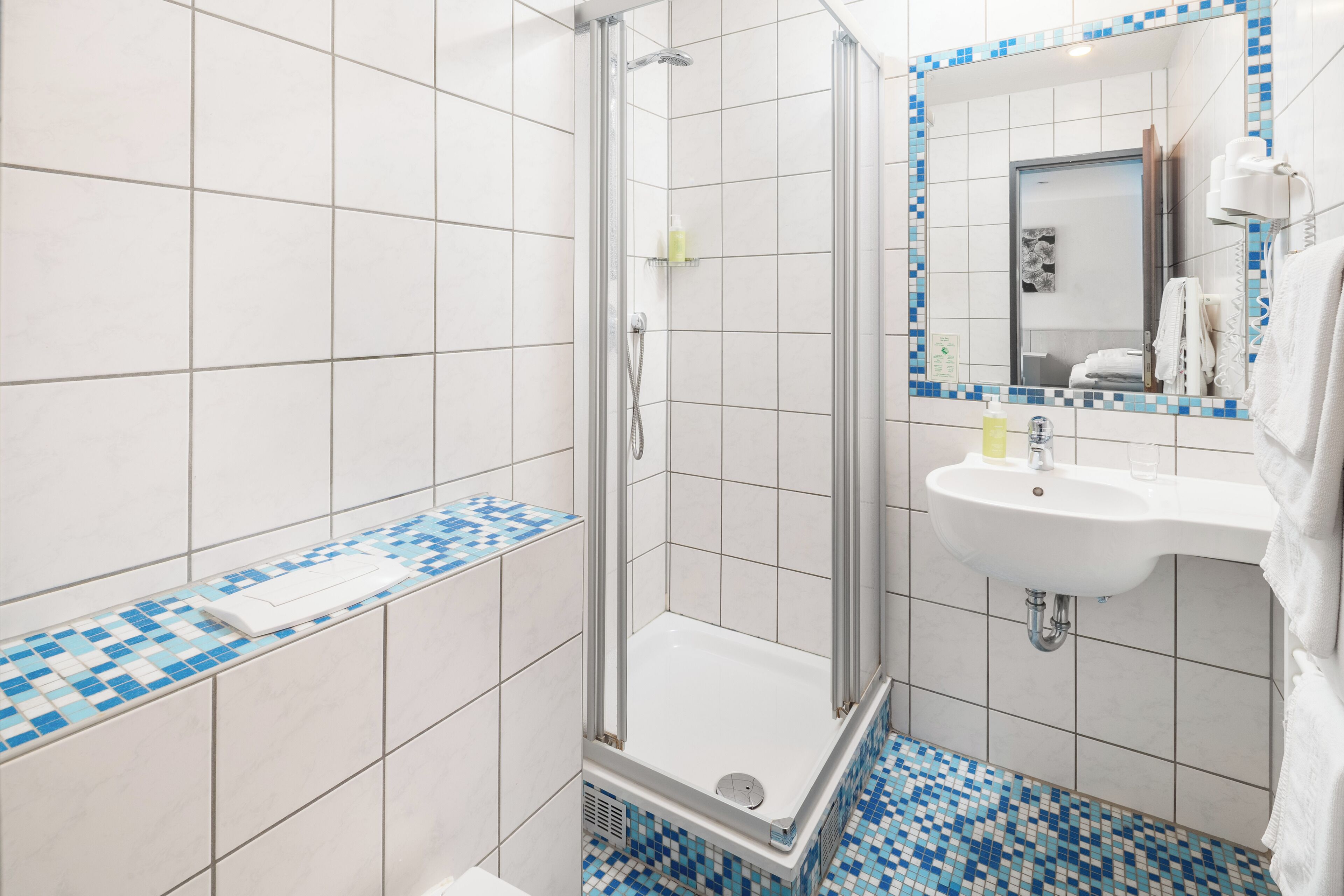 Une salle de bain avec douche, lavabo et carrelage au sol.