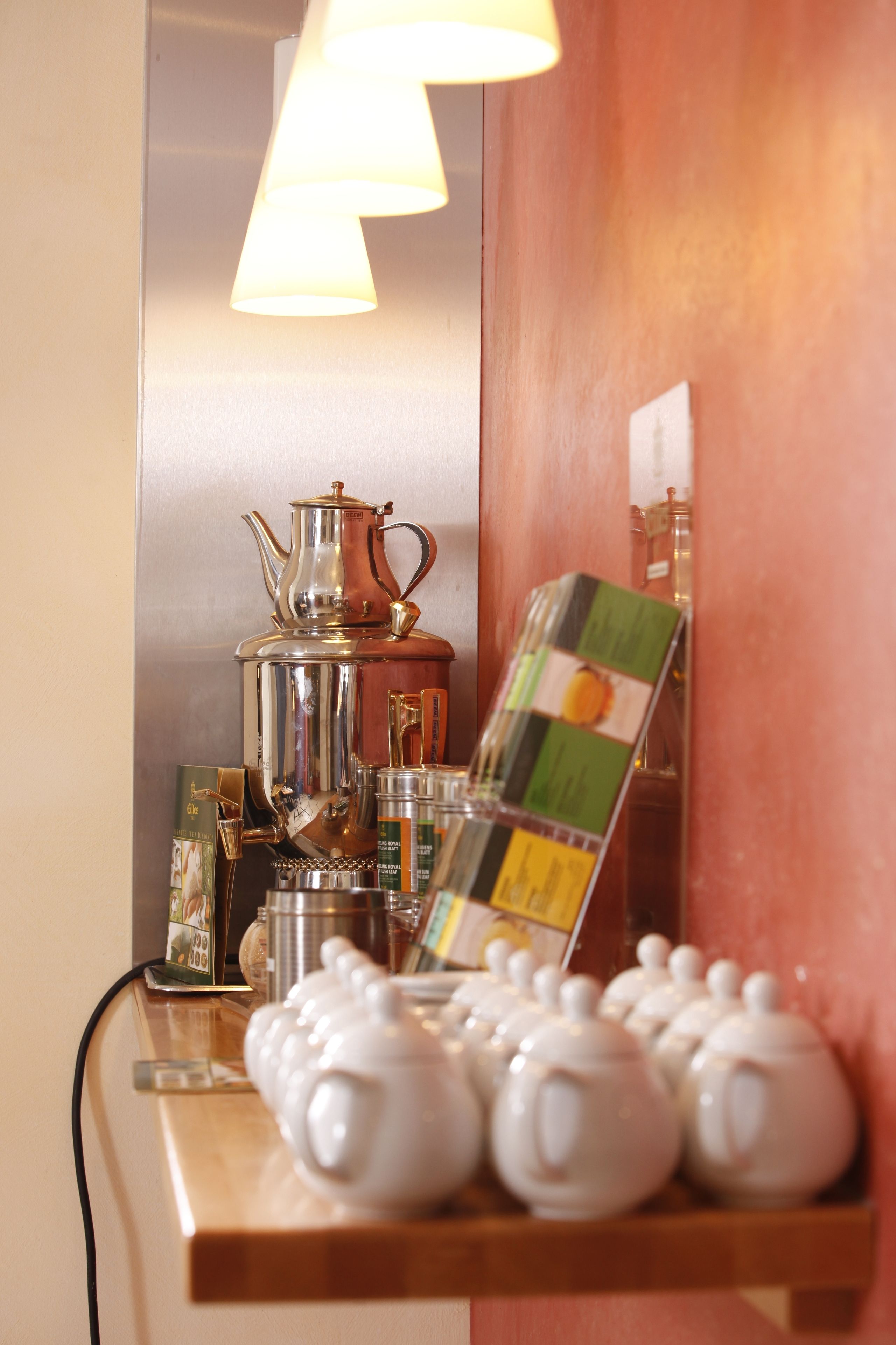 Una estación de café con cafetera, tetera y tazas de té.