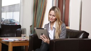 A person sitting on a leather couch in a room with a wooden table and a glass of water.