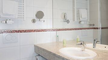 A modern bathroom with a double sink, a toilet, and a large mirror.