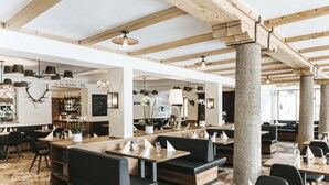 Un restaurante con vigas de madera, suelo de piedra y asientos tapizados en negro.