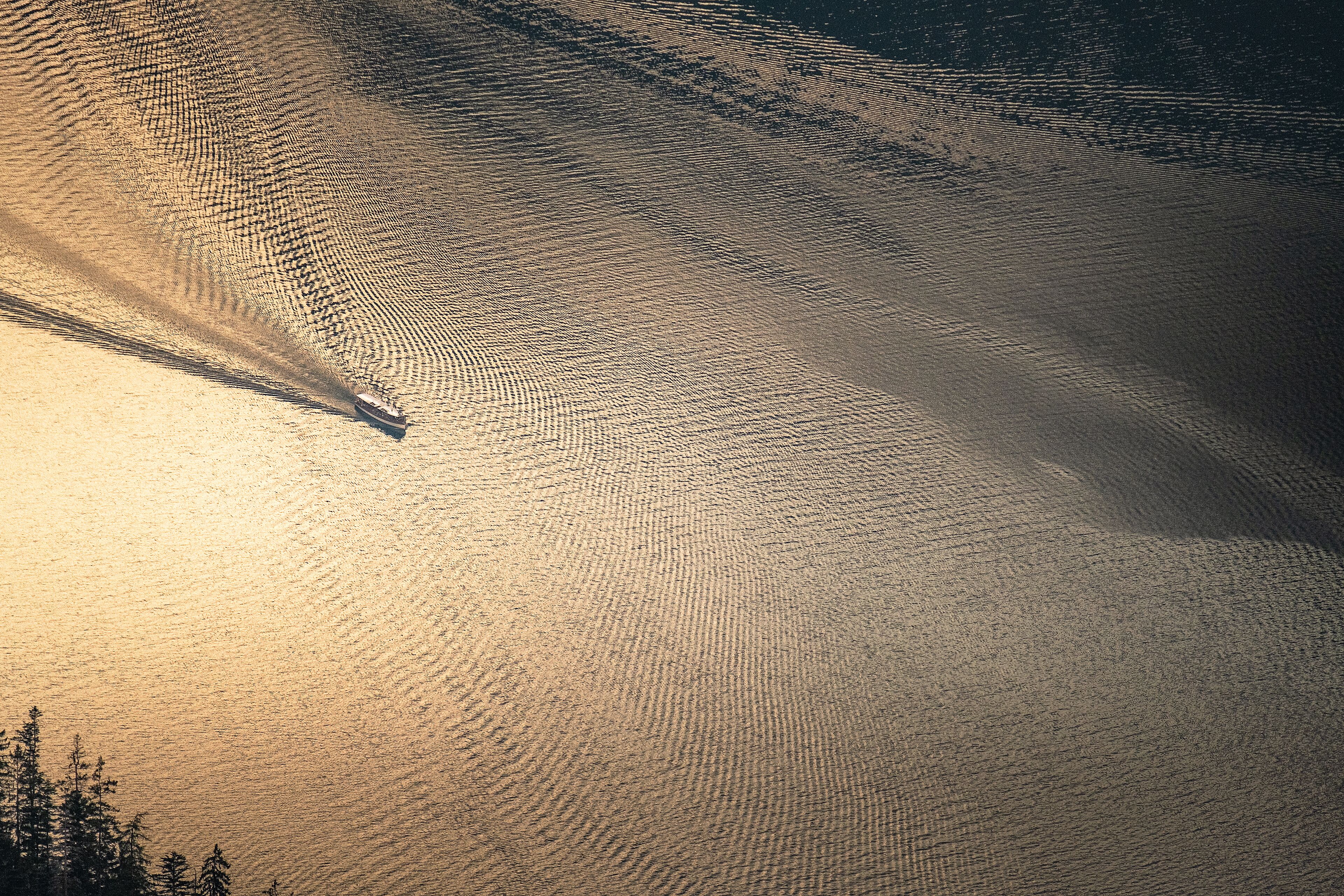 A boat on a calm lake with ripples, surrounded by a forested area.