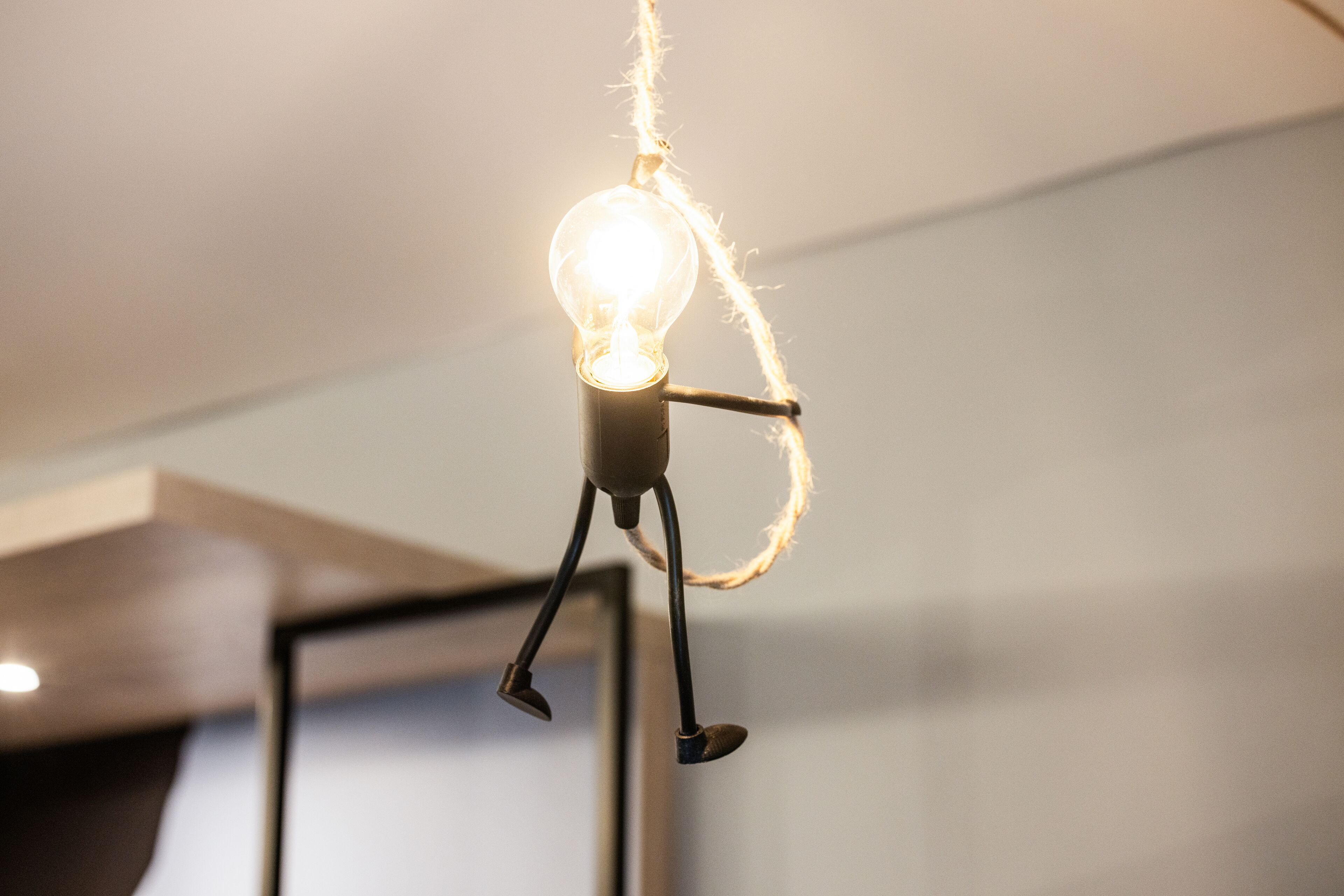 Una lámpara con un diseño singular que recuerda a una figura, con una bombilla brillante por cabeza y un cable por cuerpo.