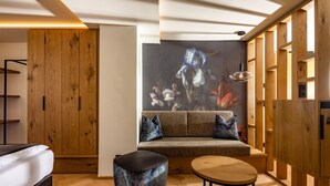 Una sala de estar moderna con sofá, reposapiés y mesa de centro, paneles de madera y una gran obra de arte floral en la pared.