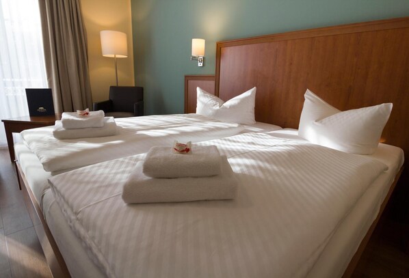 A hotel room with a large bed, two bedside tables, a chair, and two wall-mounted lamps.