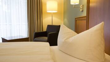 Ein Hotelzimmer mit einem Bett, einem Sessel, einer Lampe und einer Wandleuchte.