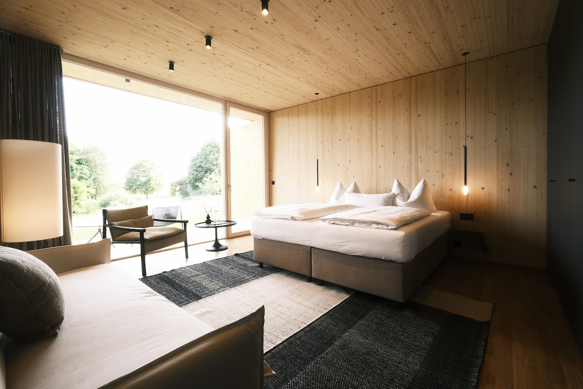 A modern bedroom with a large bed, a desk, and a chair.