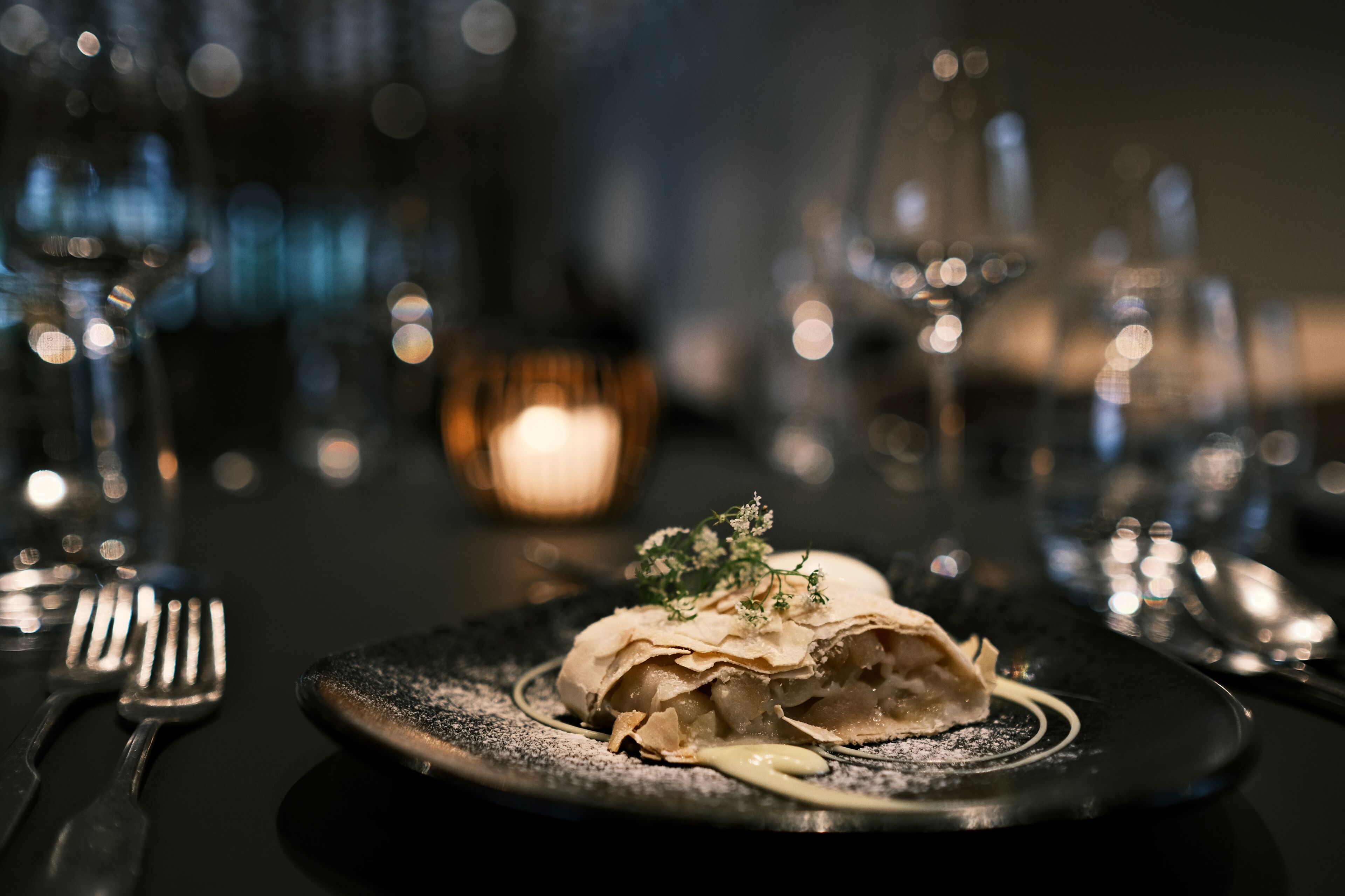 Un postre en un plato con una vela al fondo.