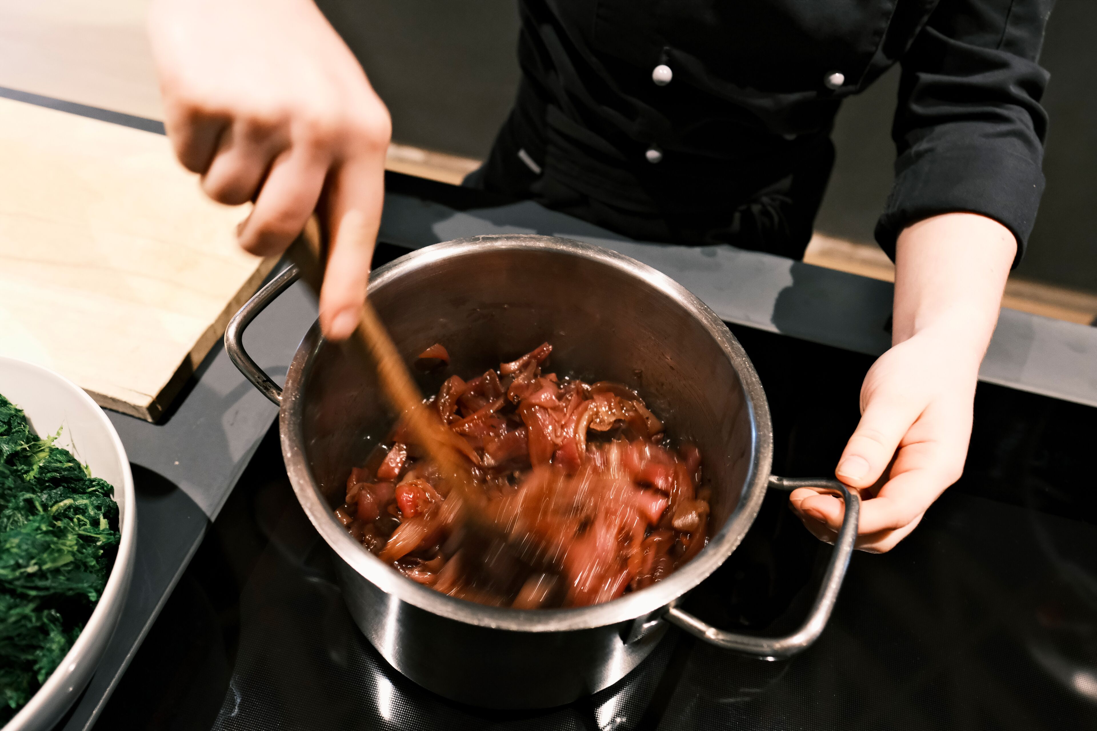 A person cooking in a kitchen with a pot on a stove.