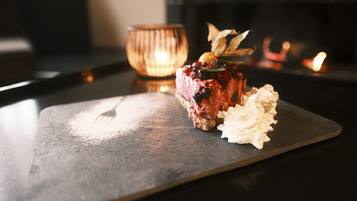 Un postre sobre un plato de pizarra con una vela al fondo.