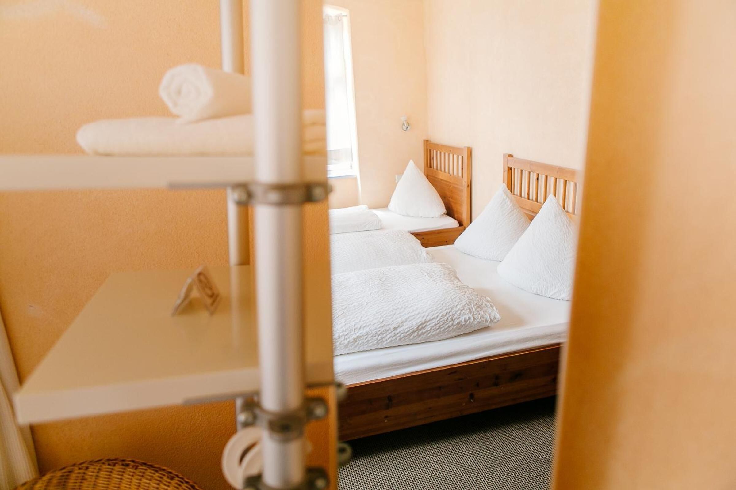 A hotel room with a bunk bed, a small table, and a window.