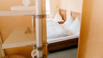 A hotel room with a bunk bed, a small table, and a window.