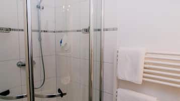 Un área de ducha con paredes de vidrio, un cabezal de ducha de mano y un accesorio de ducha manual.