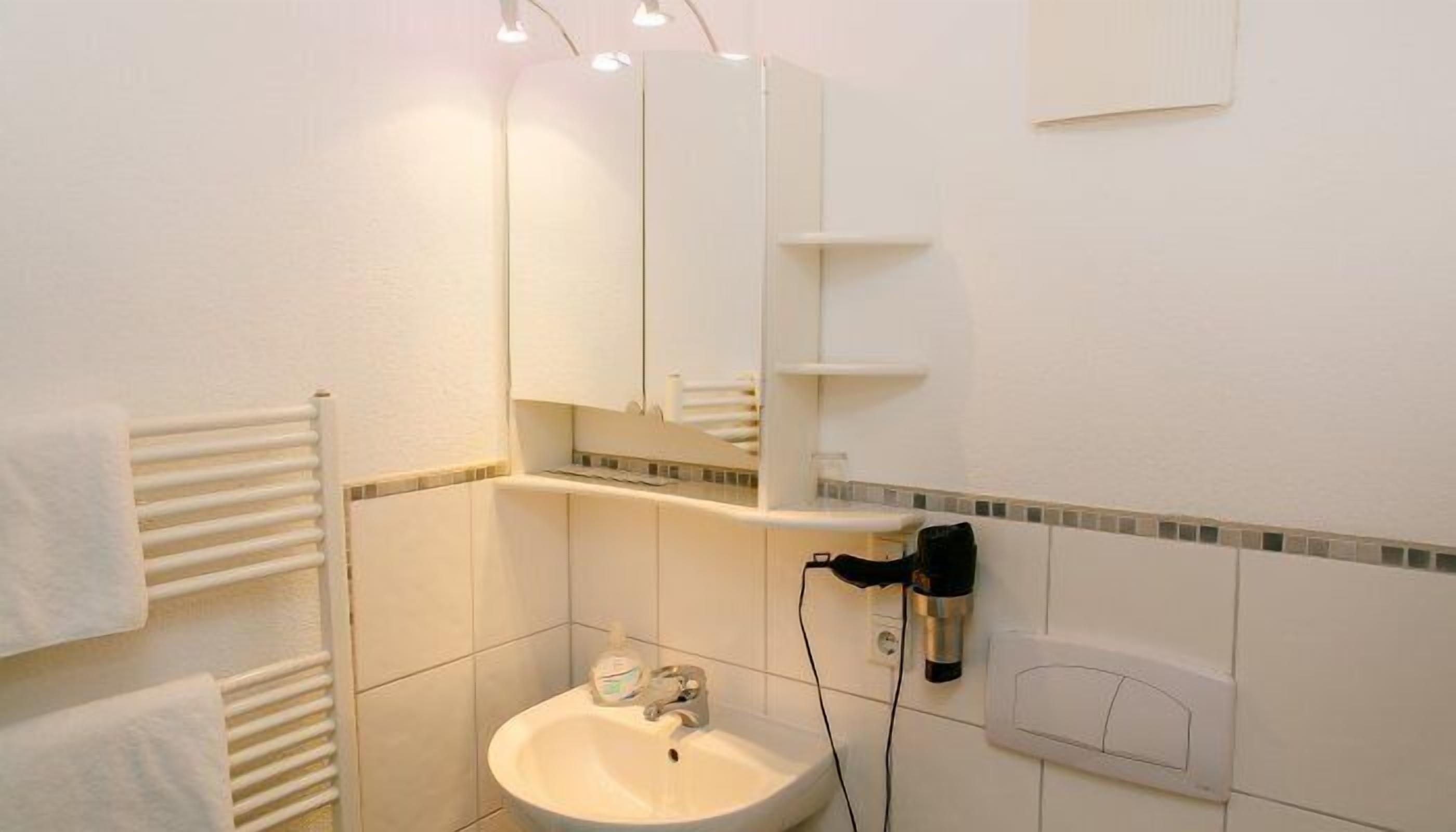 A bathroom with a white sink, a mirror, and a towel rack.