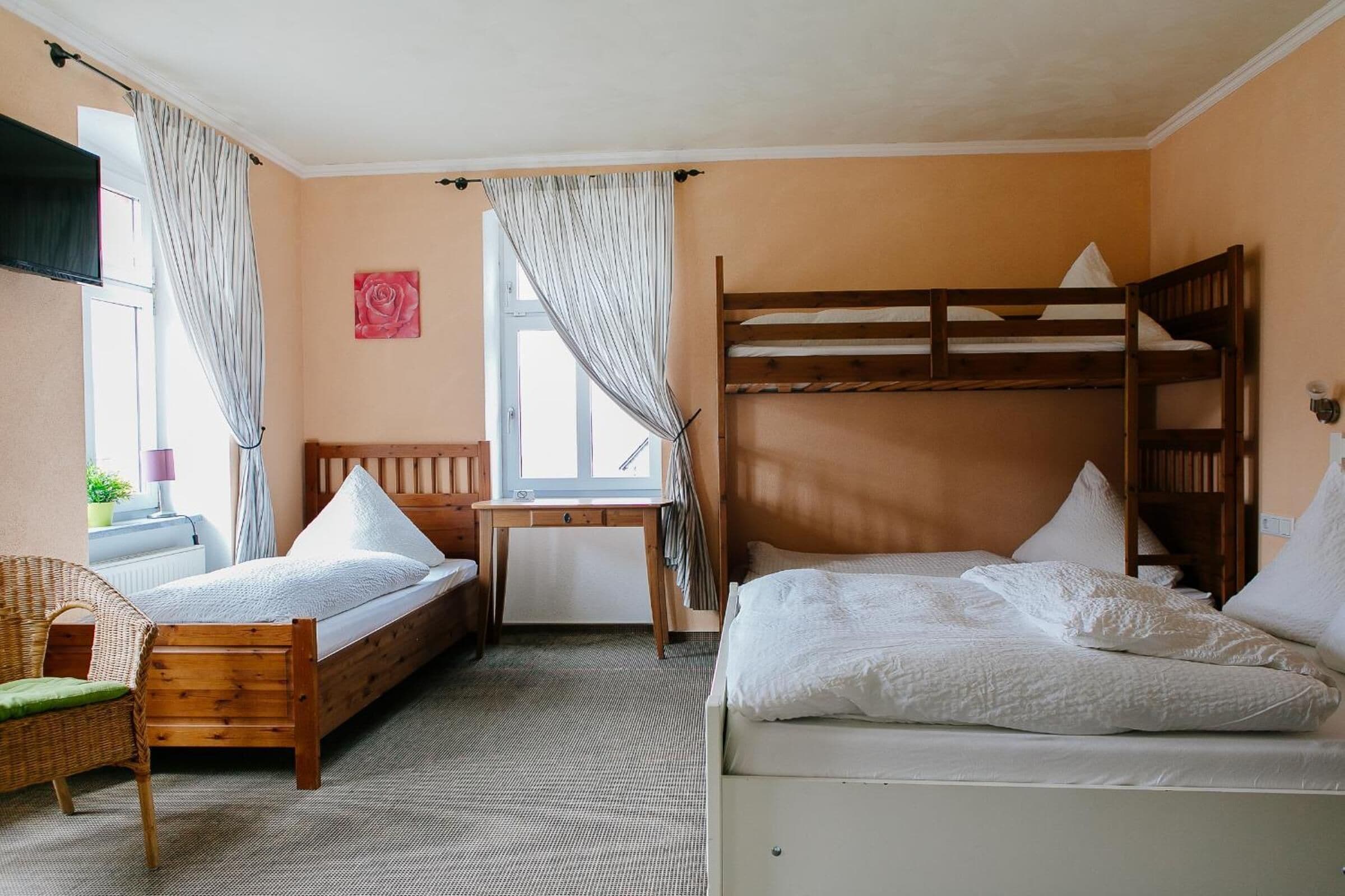A room with two bunk beds, a wooden desk, a chair, and a window with curtains.
