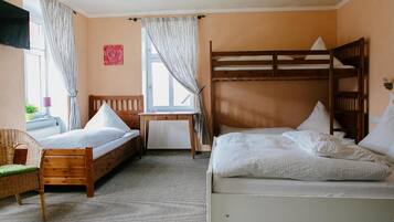 Una habitación con dos literas, un escritorio de madera, una silla y una ventana con cortinas.