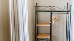 Una estantería metálica con tres repisas, posiblemente para guardar o exhibir objetos, en una habitación con cortinas.
