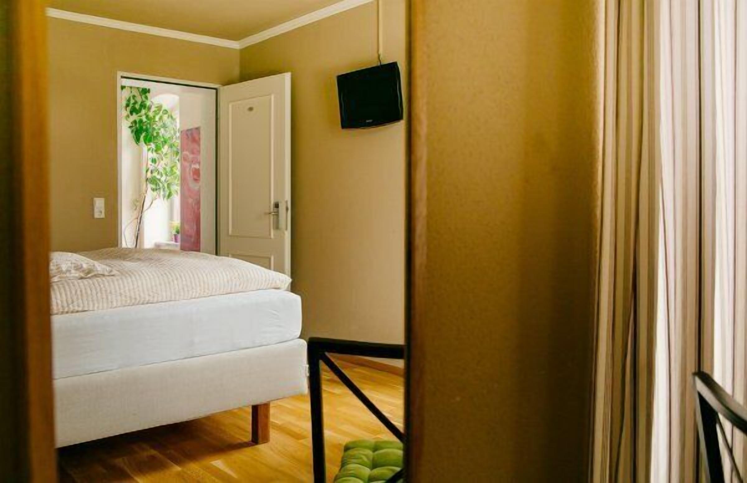 Ein Schlafzimmer mit einem Bett, einem Fernseher und einer Tür zu einem weiteren Raum.