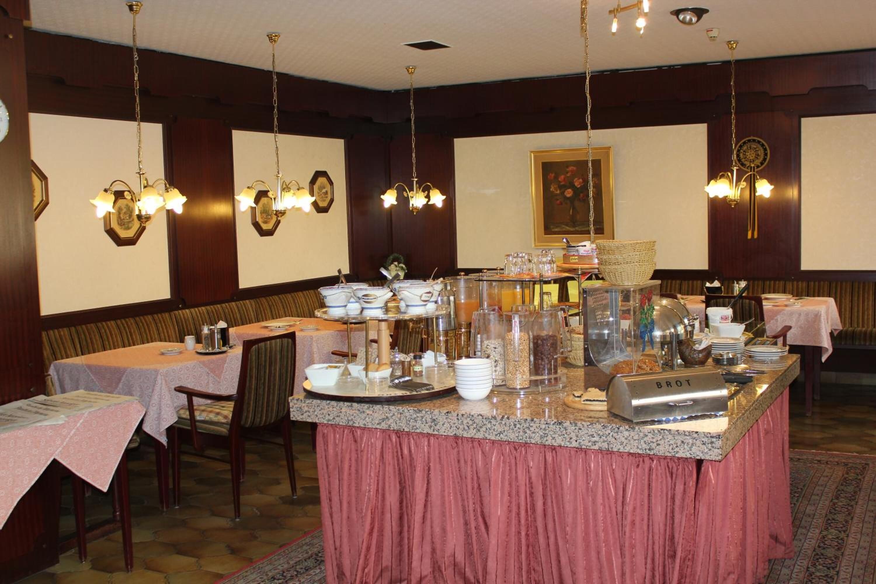 Een eetruimte met meerdere tafels, een buffet en hangende kroonluchters.