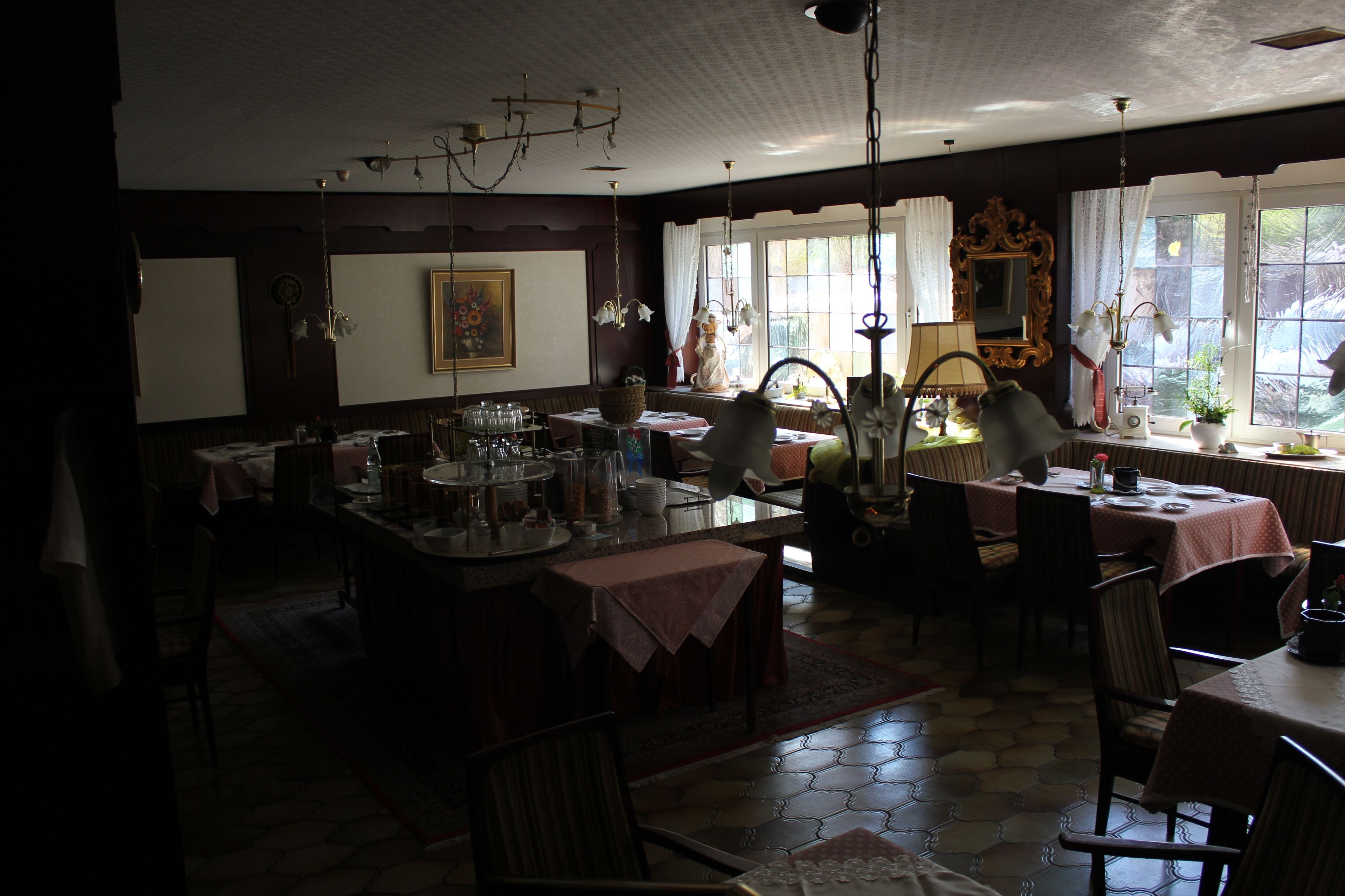 Un comedor con una isla central, varias mesas, sillas y un amplio ventanal con cortinas.