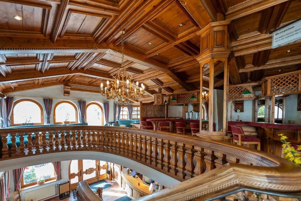 A grand interior with a high ceiling, ornate wooden beams, and a central staircase.