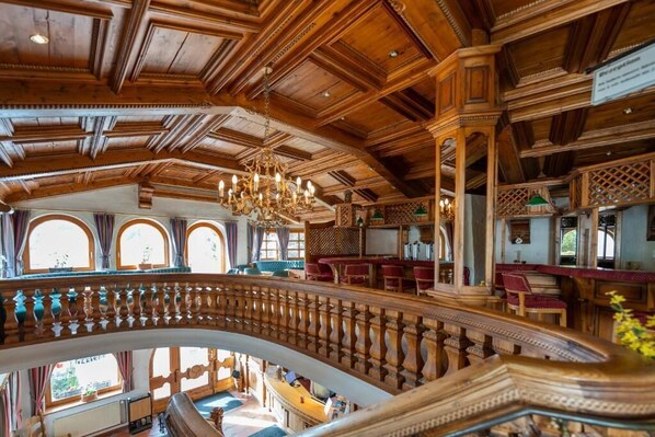 A grand interior with a high ceiling, ornate wooden beams, and a central staircase. - Hotels Am Kranichsee (Goslar)