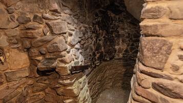 Explore a narrow, stone-walled corridor leading to a secluded space.